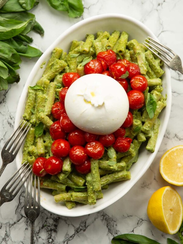 overhead shot of pistachio pesto pasta in large dish with tomatoes and burrata