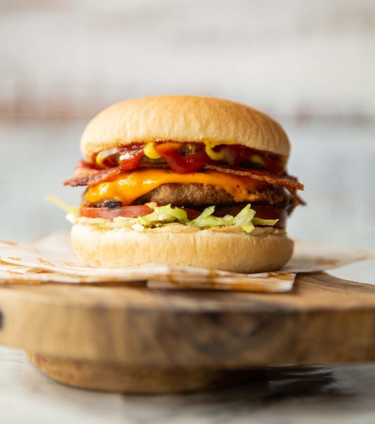 sausage smash burger on wooden board showing layers