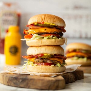 2 sausage smash burgers stacked on each other on wooden chopping board