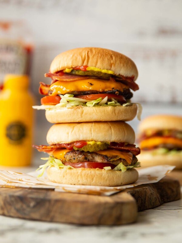 2 sausage smash burgers stacked on each other on wooden chopping board