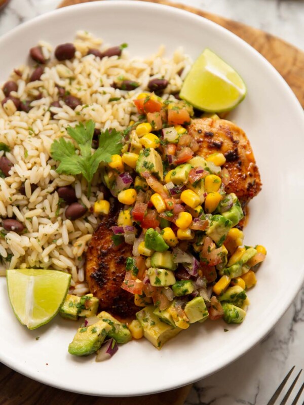 cajun chicken avocado corn salsa served with rice on small white plate