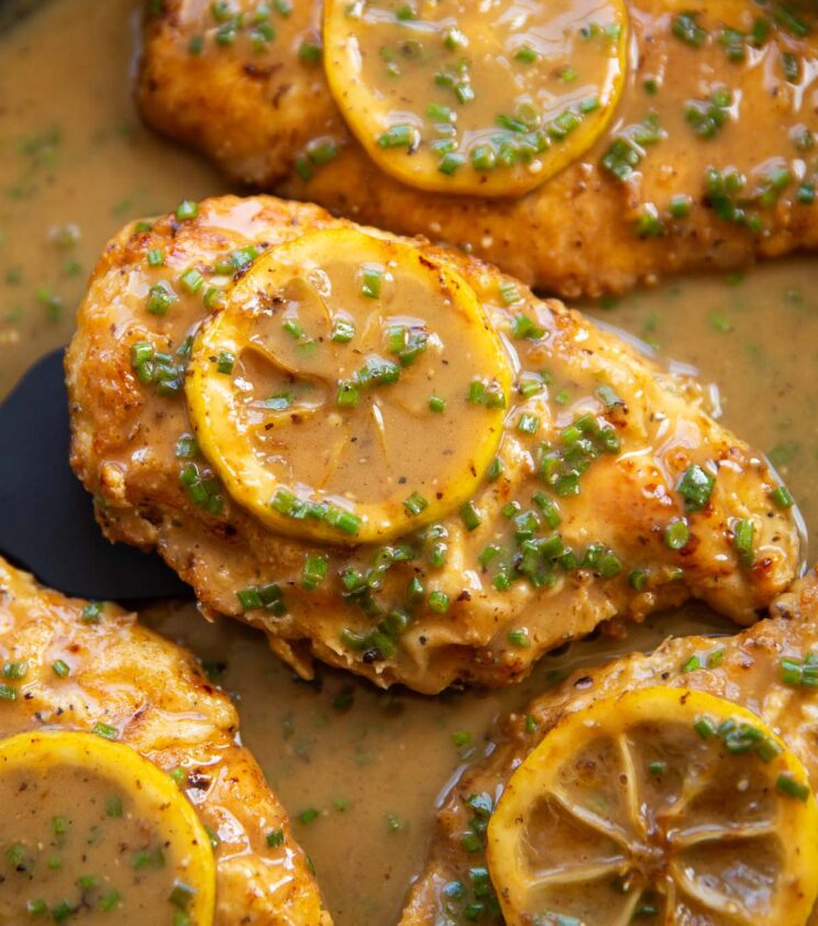 close up shot of chicken francese in pan garnished with lemon slice