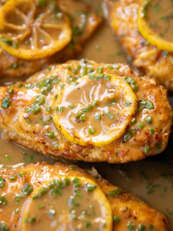 close up shot of chicken francese in large pan with lemon slice on top