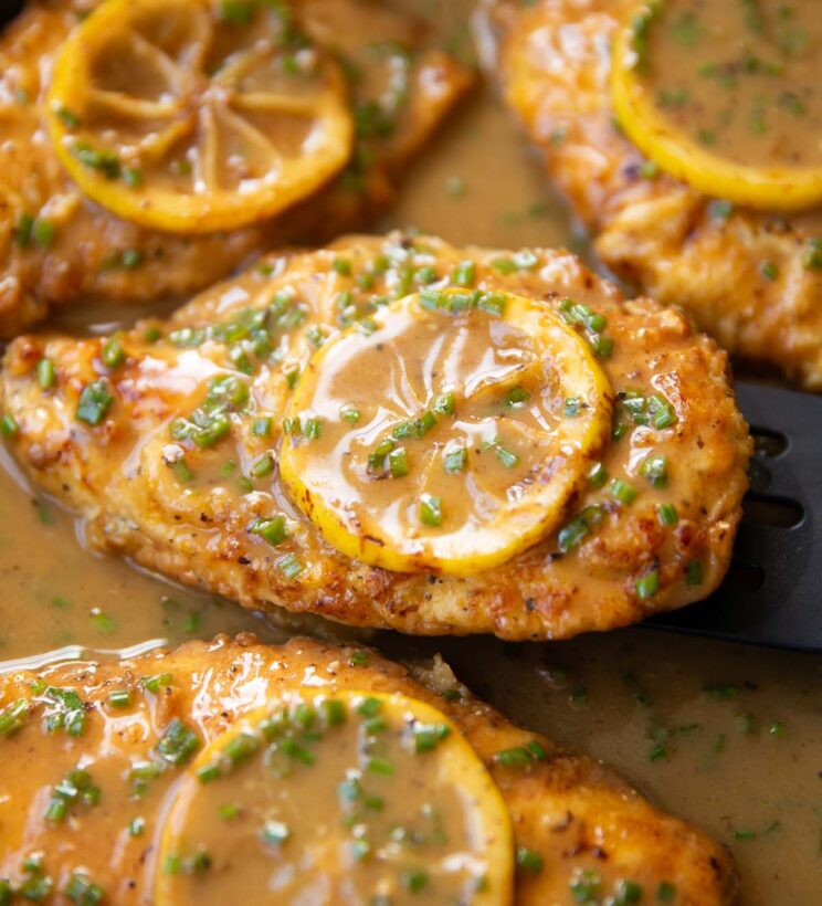 close up shot of chicken francese in large pan with lemon slice on top