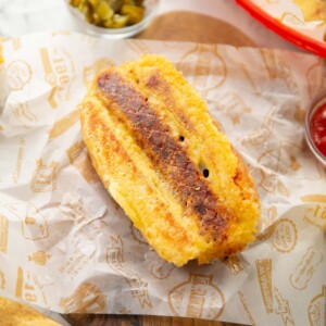 grilled cheese hot dog on chopping board with jalapeños in background