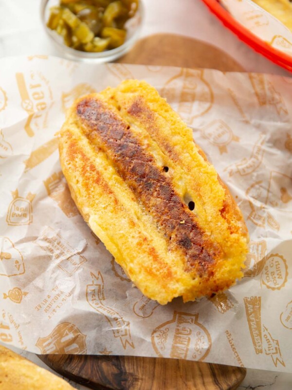 grilled cheese hot dog on chopping board with jalapeños in background