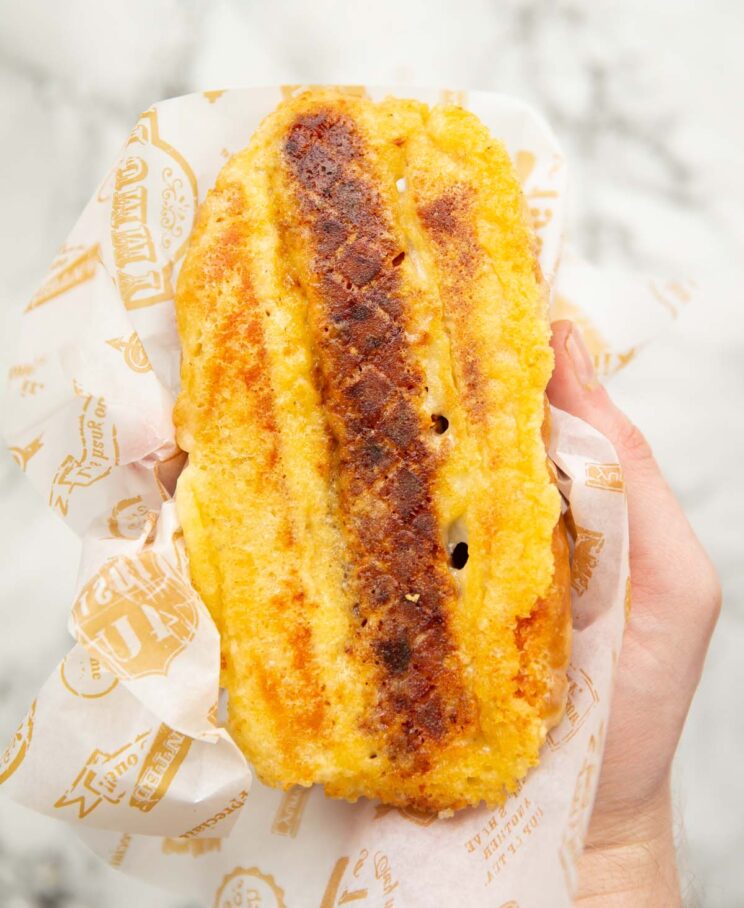 close up overhead shot of hand holding grilled cheese hotdog