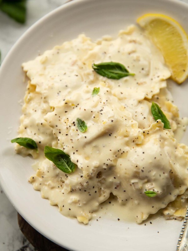 ravioli with lemon cream sauce served on small white plate garnished with basil