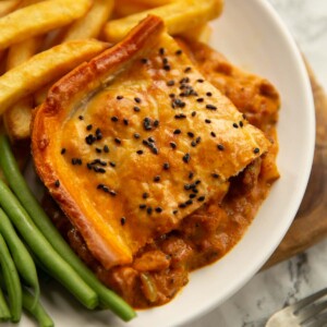 curry chicken pie on small white plate with chips and green beans