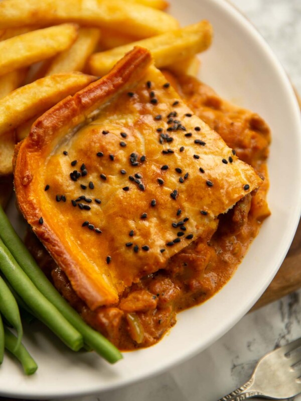 curry chicken pie on small white plate with chips and green beans