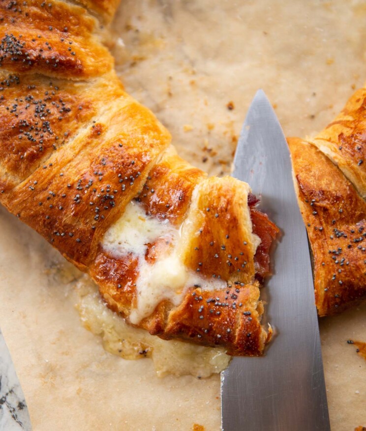 close up shot of knife slicing into cranberry bacon brie croissant wreath