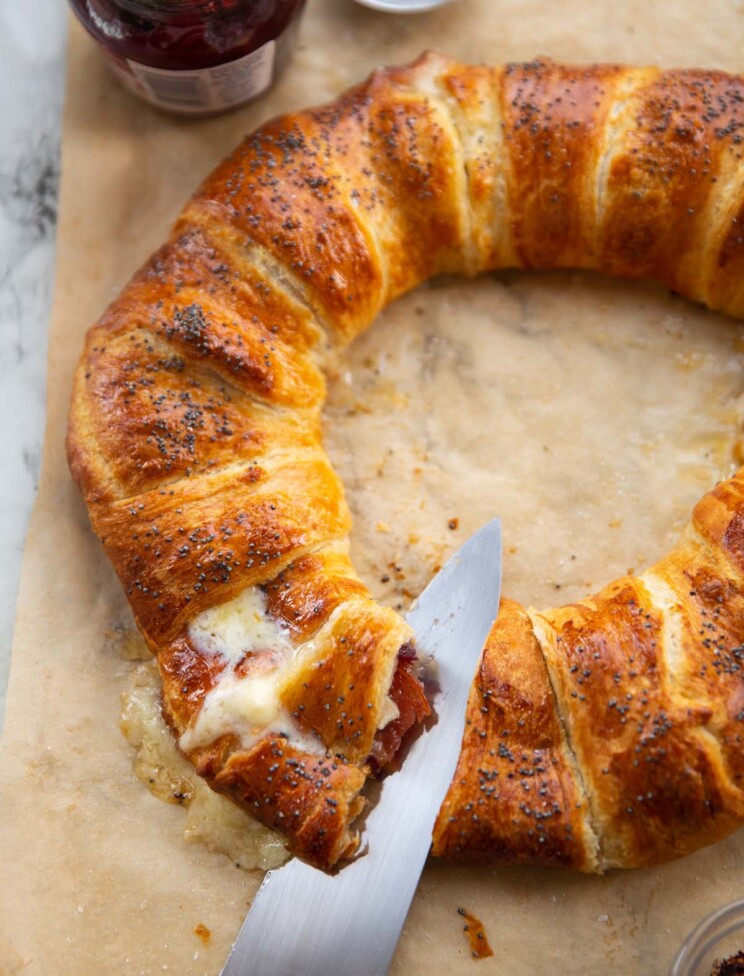 cranberry bacon brie wreath with knife slicing in and showing filling