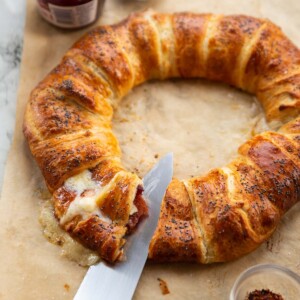 croissant wreath on brown baking paper with knife slicing into it