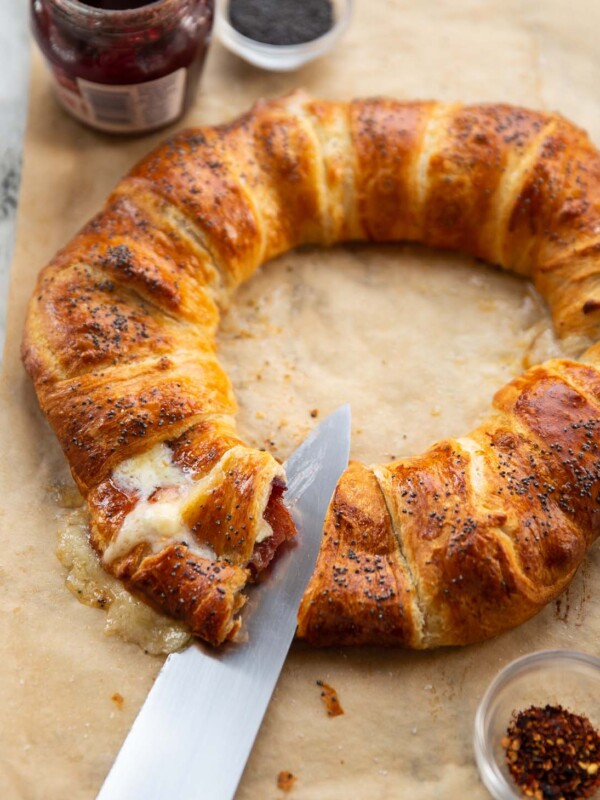 croissant wreath on brown baking paper with knife slicing into it