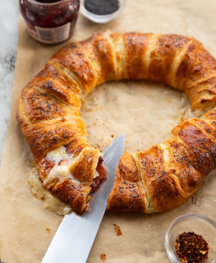 croissant wreath on brown baking paper with knife slicing into it