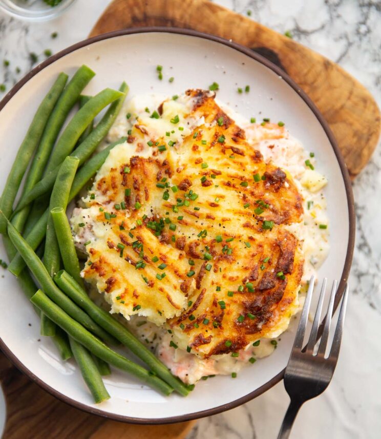 overhead shot of fish pie served on small white plate with green beans