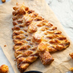 puff pastry Christmas tree on brown baking paper dusted with parmesan