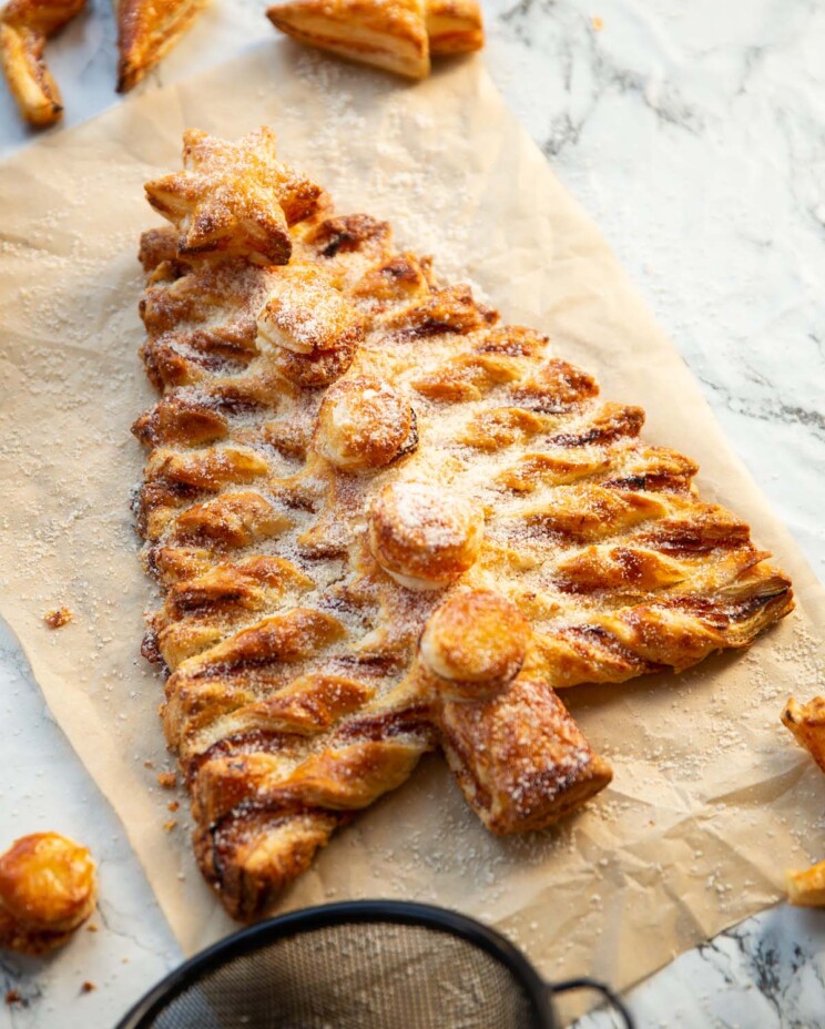 puff pastry Christmas tree on brown baking paper dusted with parmesan