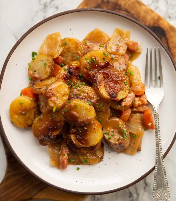 overhead shot of sausage potato bake served on small white plate with silver fork