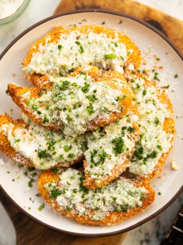 garlic parmesan chicken tenders on small white plate on wooden board