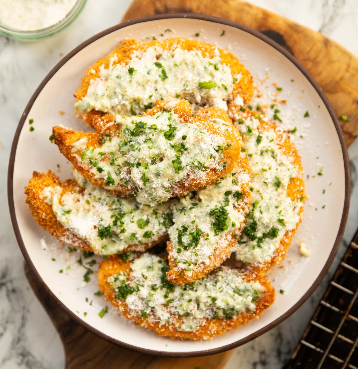 garlic parmesan chicken tenders on small white plate on wooden board