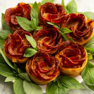 pepperoni pizza roses on small white plate with fresh basil