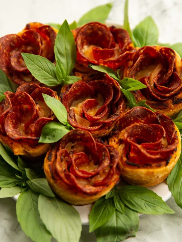 pepperoni pizza roses on small white plate with fresh basil