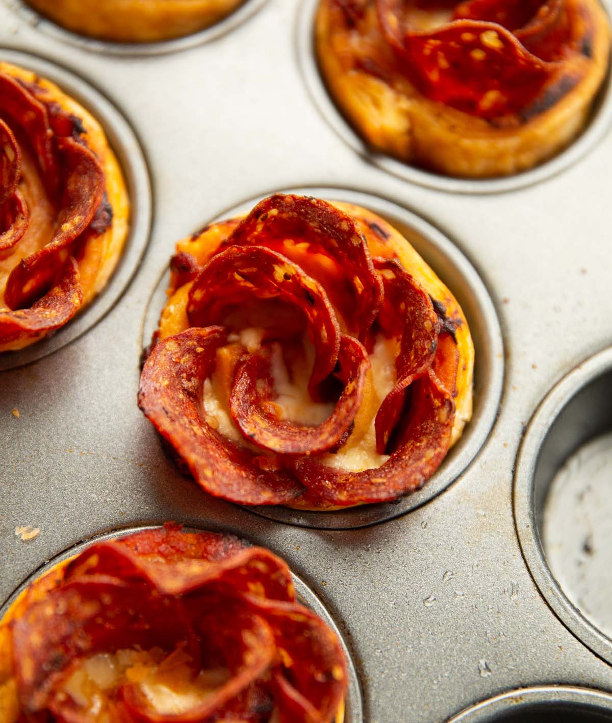 close up shot of pizza roses in muffin tin fresh out the oven