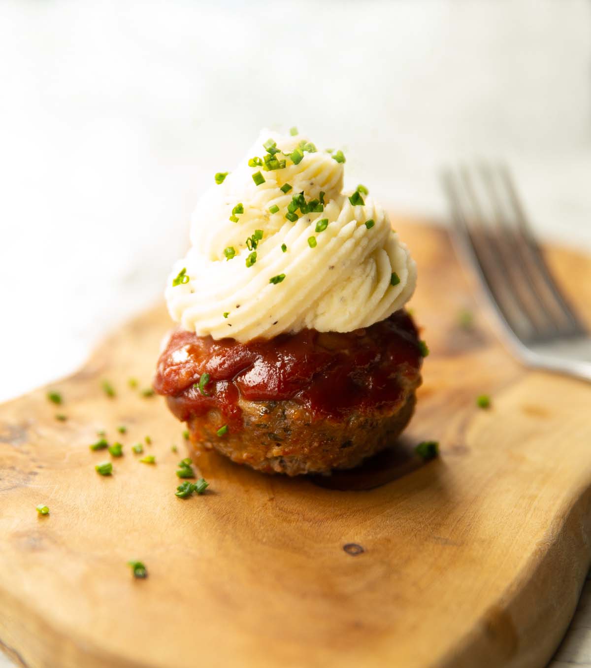 meatloaf cupcake on wooden chopping board garnished with chives