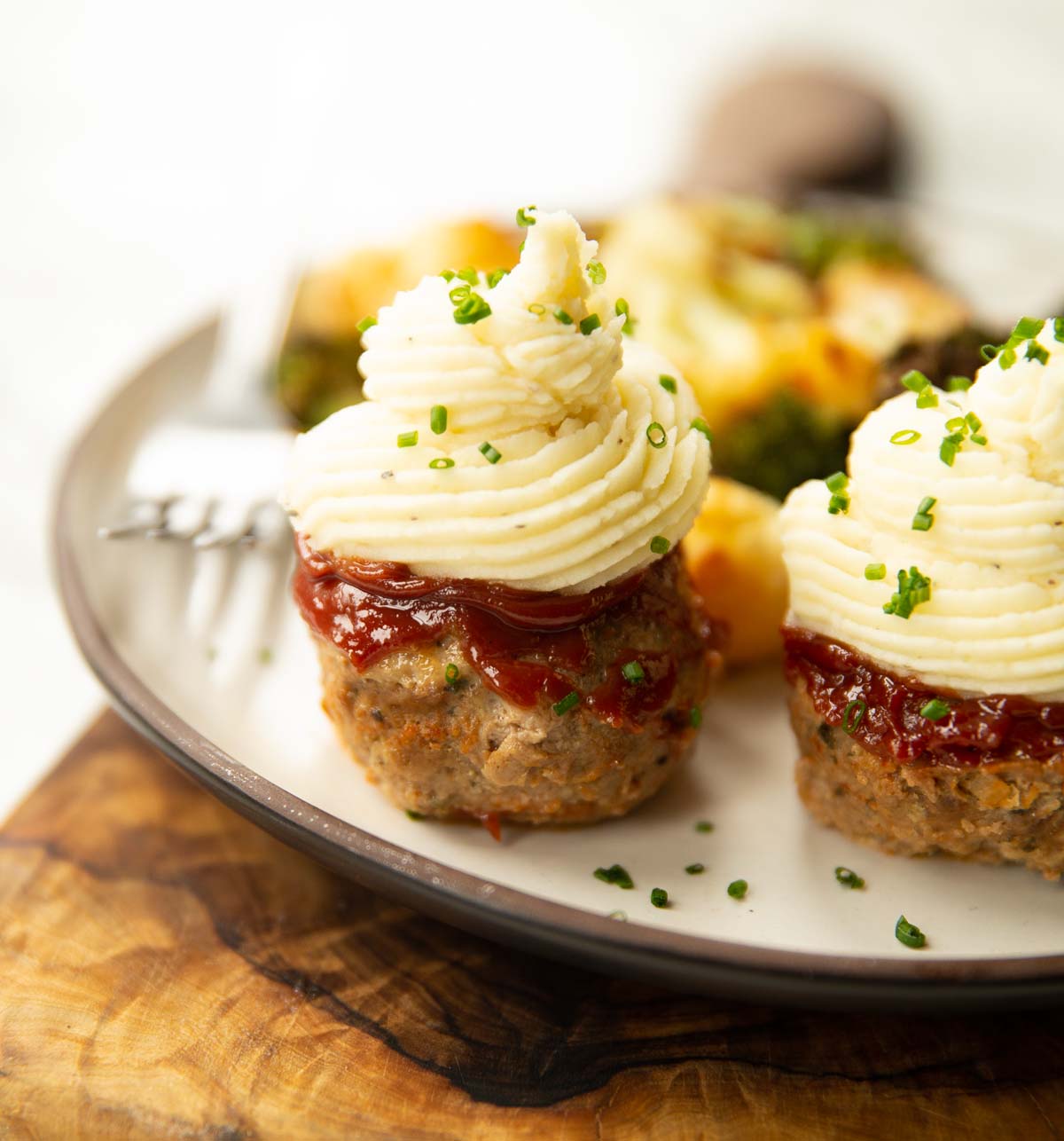 mini meatloaf on small white plate on wooden chopping board