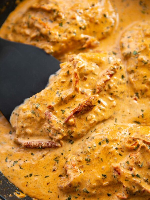 close up shot of spatula lifting sun dried tomato chicken in pan